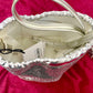 Inside view of Paco Rabanne silver shoulder/wrist bag with both straps shown, on red velvet fabric background.