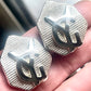 Close-up of vintage YSL silver-tone hexagon earrings resting on the hand, showing the textured surface and raised YSL monogram.