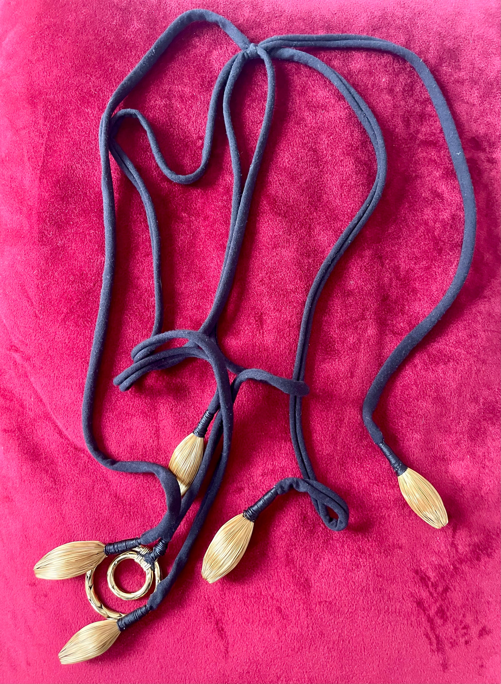 One of a kind Necklace with leaf-like pendants and Yves Saint Laurent scarf pendant on a red fabric background