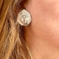 Worn by model Close-up of vintage YSL silver-tone hexagon earrings resting on the hand, showing the textured surface and raised YSL monogram.
