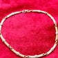 Vintage Christian Dior two-tone necklace with ribbed accents displayed on a red velvet background