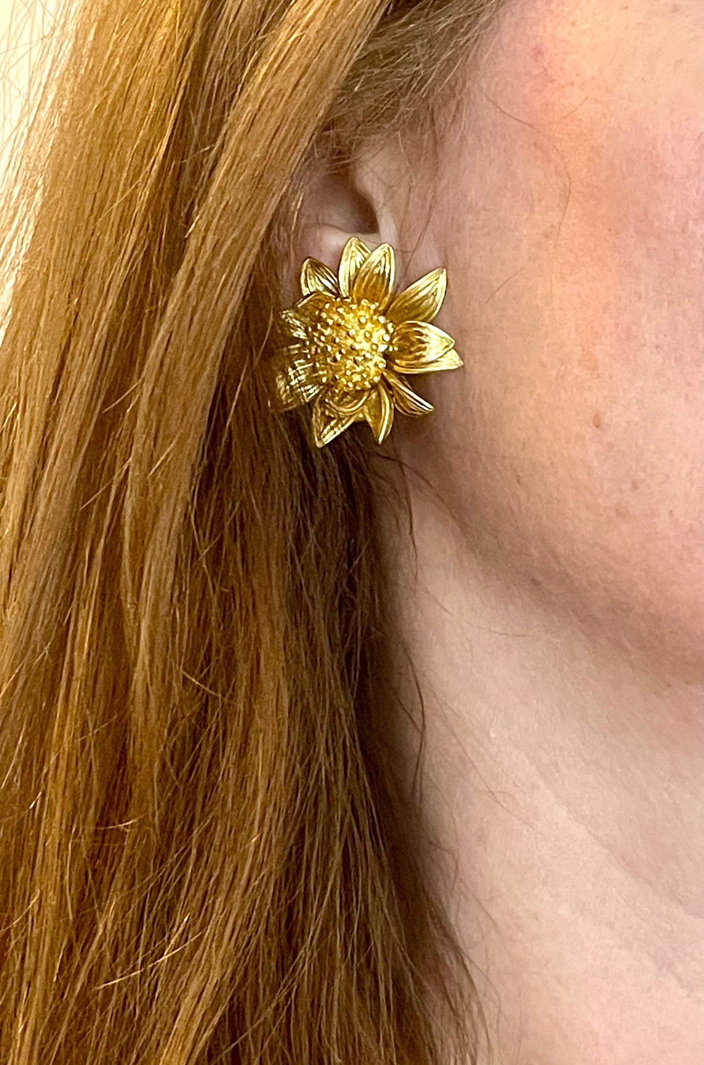 Gold sunflower vintage Orena Paris earring worn by a person with blonde hair.