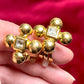 Yves Saint Laurent vintage gold tone cross clip-on earrings from the 1980s held in hand, showing rounded gold domes and square-cut center stones