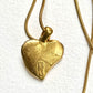 Gold heart-shaped Yves Saint Laurent pendant on a chain against a white background