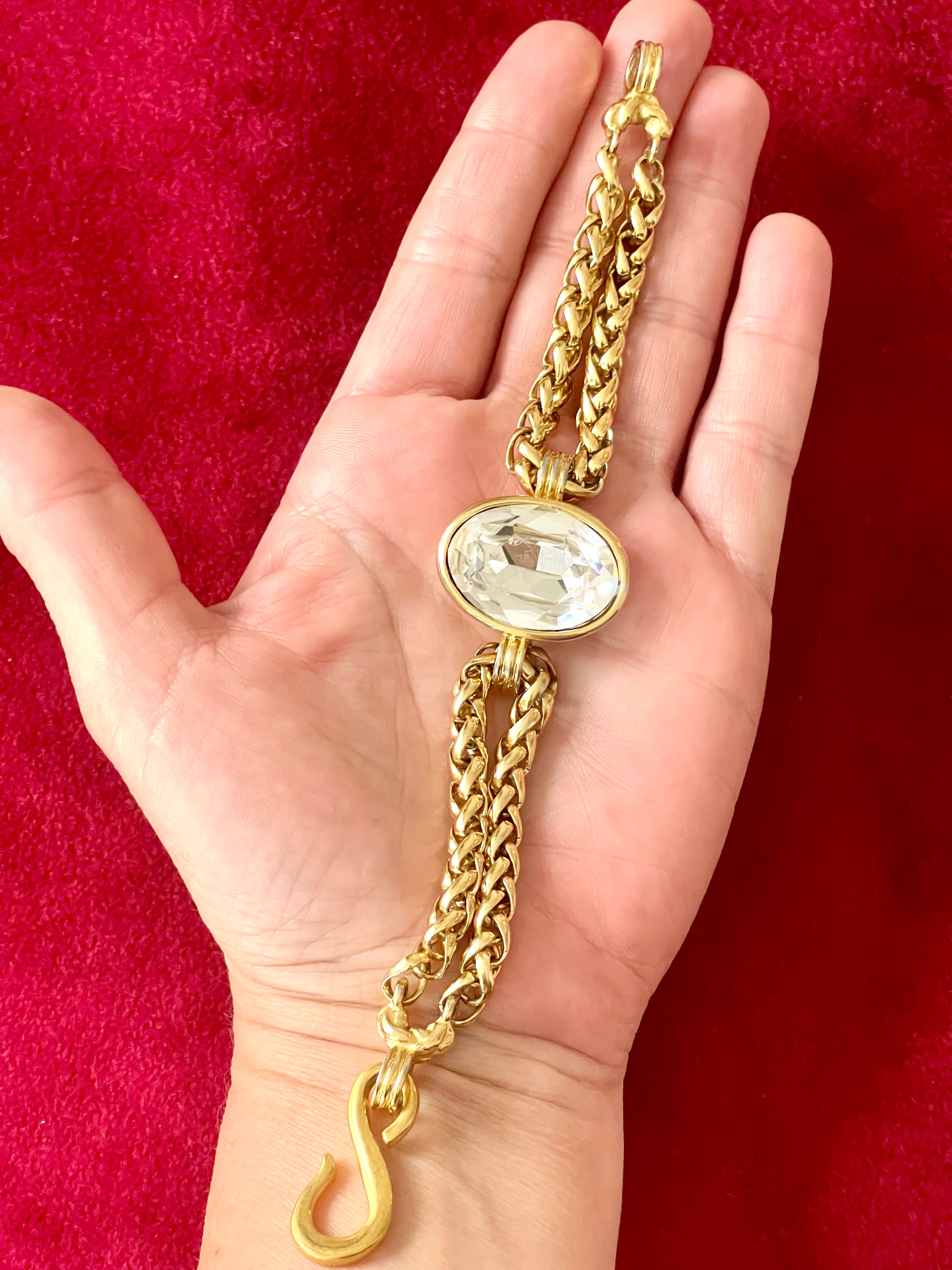 Vintage Yves Saint Laurent crystal chain bracelet signed YSL Made in France Placed in hand with a red background 