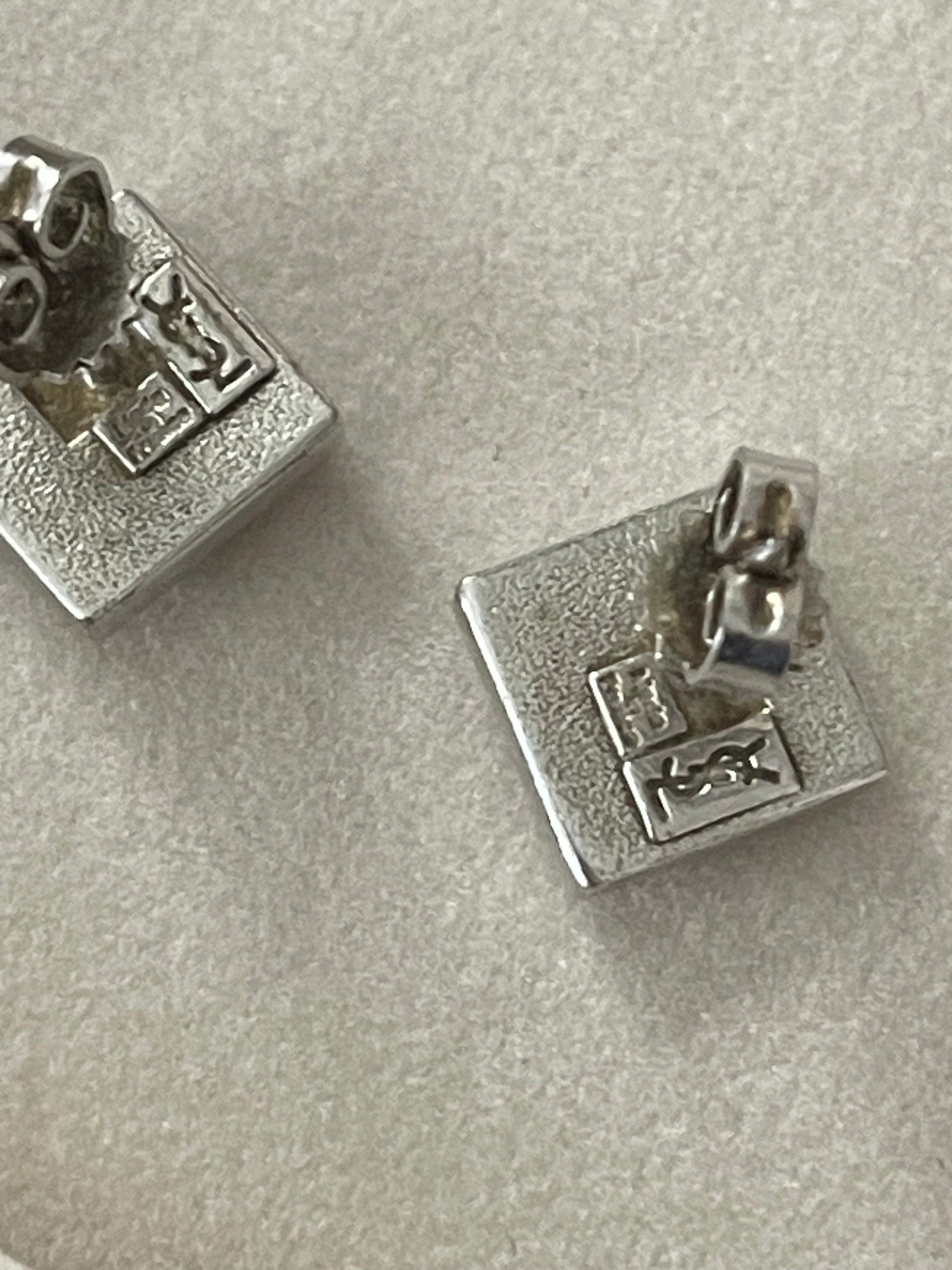 Back side view Vintage Yves Saint Laurent silver 925 earrings and pendant necklace set displayed on hand showing the tag signature of YSL made in France 