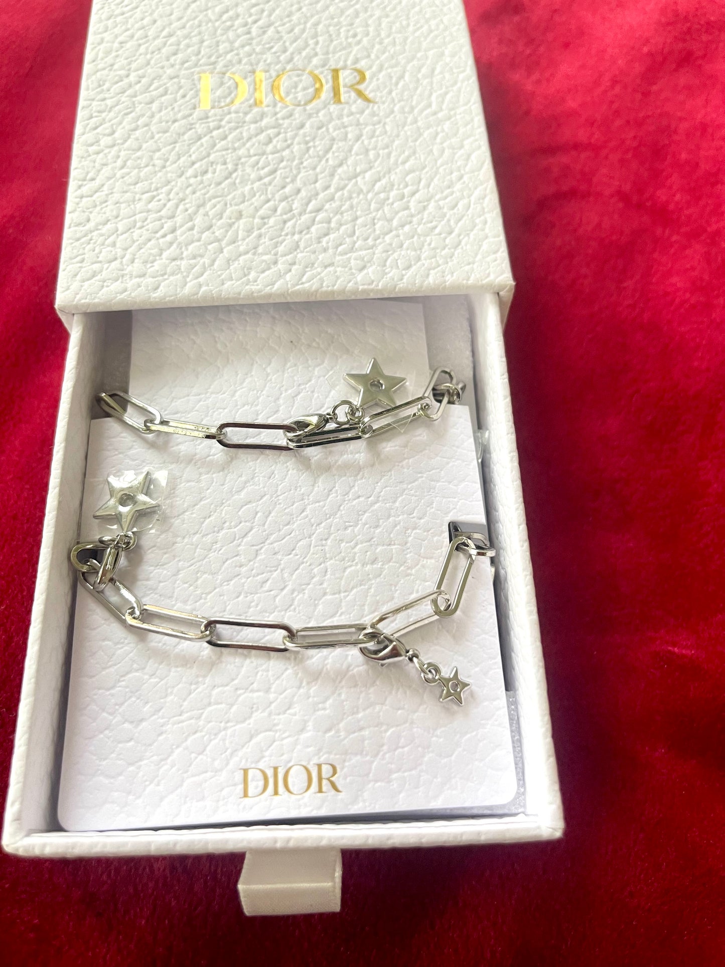 Original Dior box with upcycled Dior Beauté phone charm necklace with removable silver-tone charms on a red background 