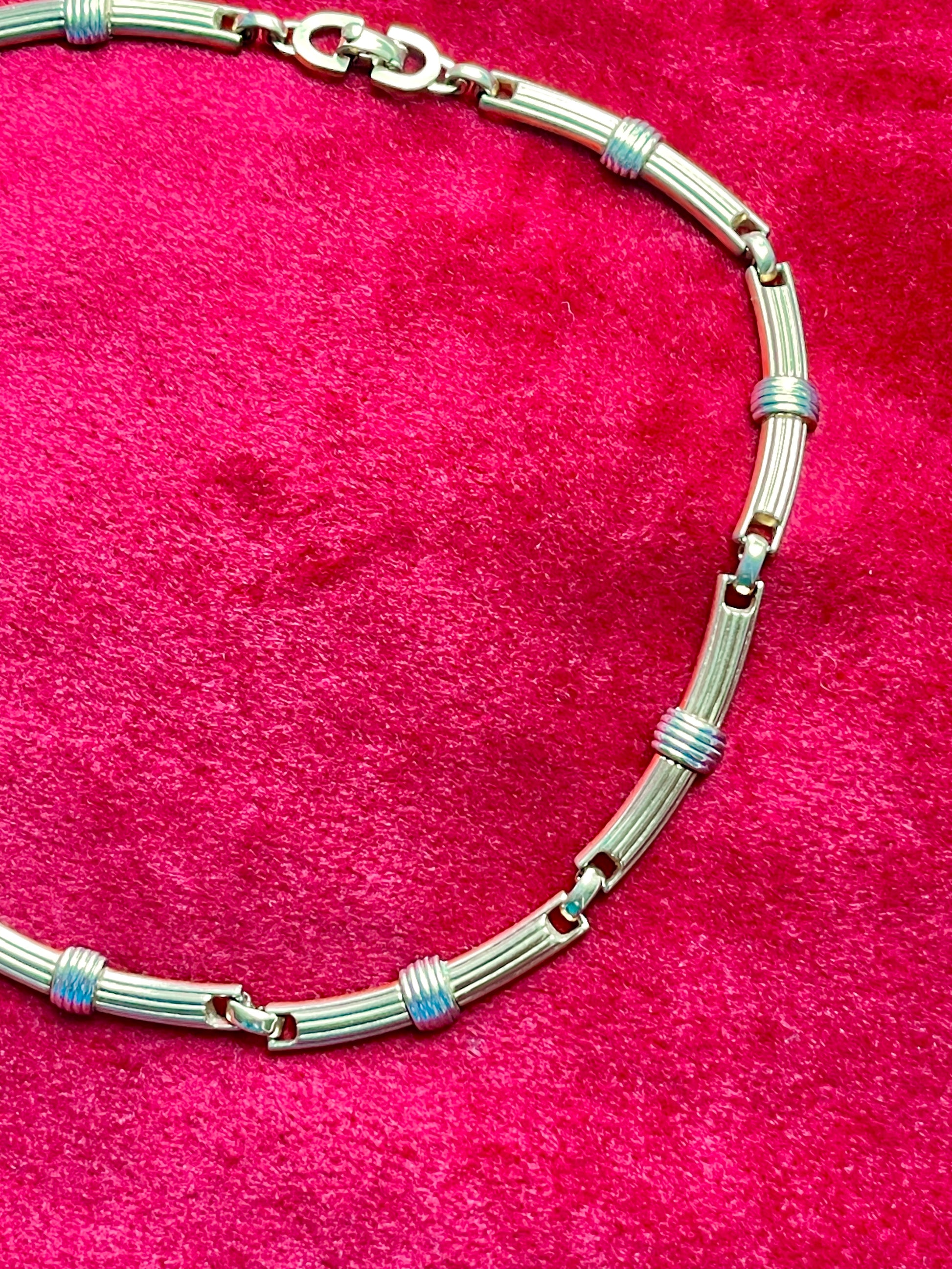 Vintage Christian Dior two-tone necklace with ribbed accents displayed on a red velvet background