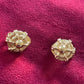 Two gold button earrings vintage Dior on a pink fabric background