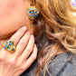 Close-up of a person wearing a gold and blue heart-shaped earring and ring vintage Yves Saint Laurent 