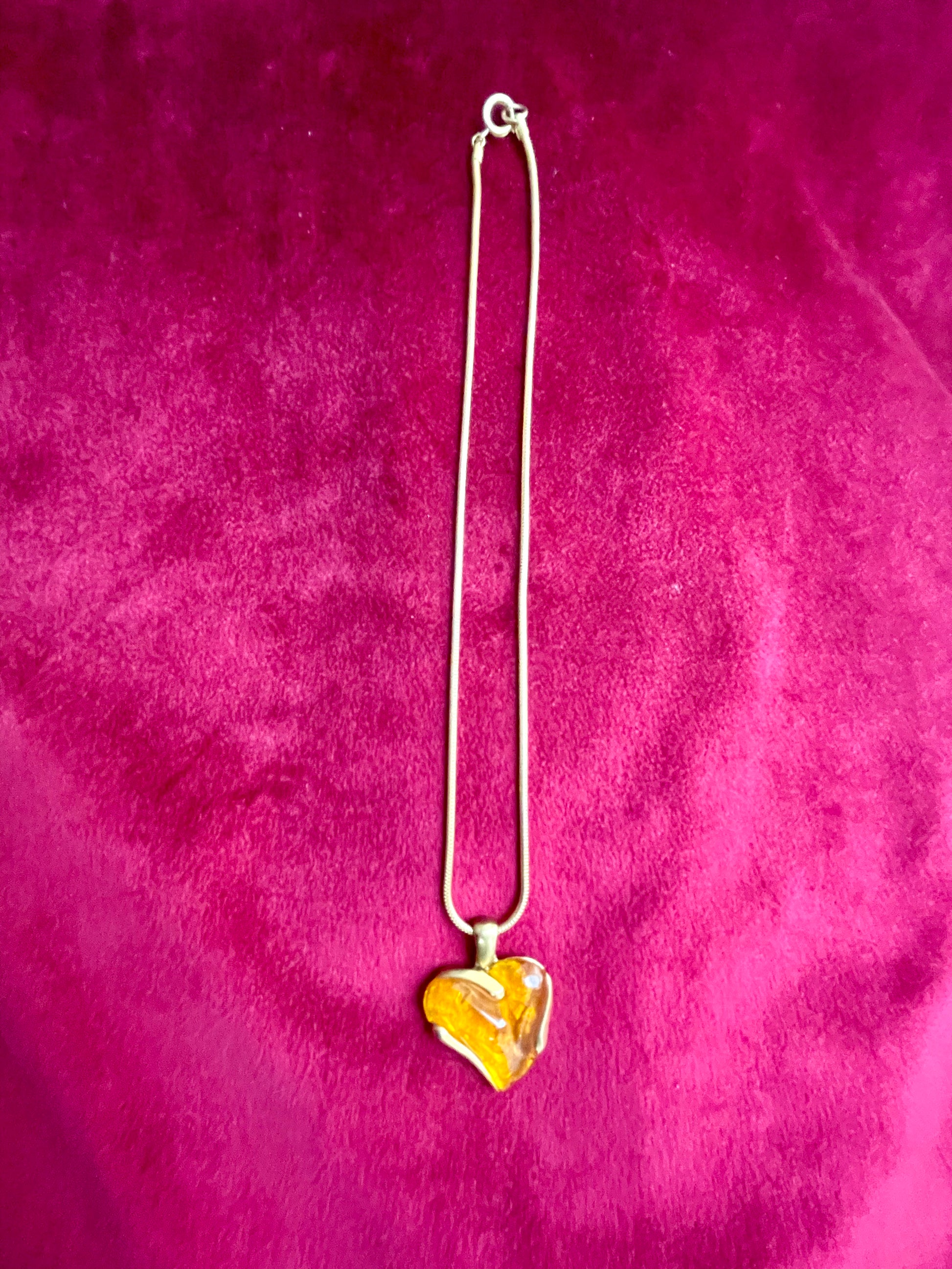 Elegant gold-tone chain with bright orange resin pendant YSL necklace on pink background 