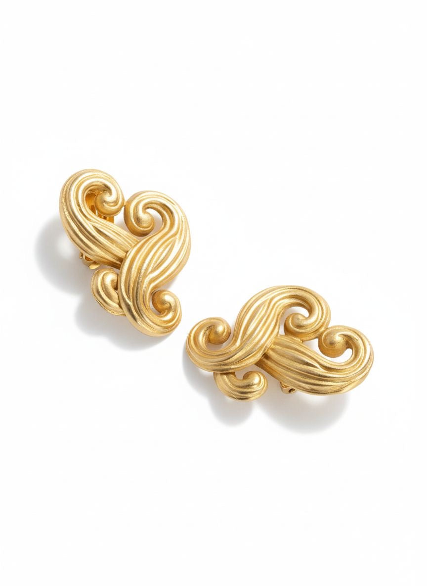 Vintage Nina Ricci swirly heart earrings in matte gold plated metal, signed Nina Ricci Paris, 1990s design on a white background 