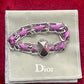 Dior Gourmet Purple braided bracelet with silver chain on a Dior branded pouch against a red background