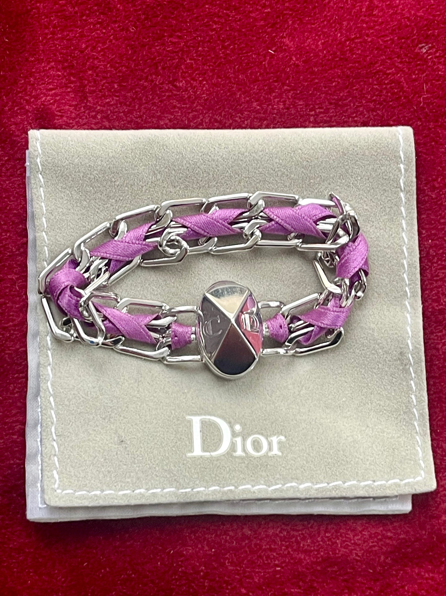 Dior Gourmet Purple braided bracelet with silver chain on a Dior branded pouch against a red background