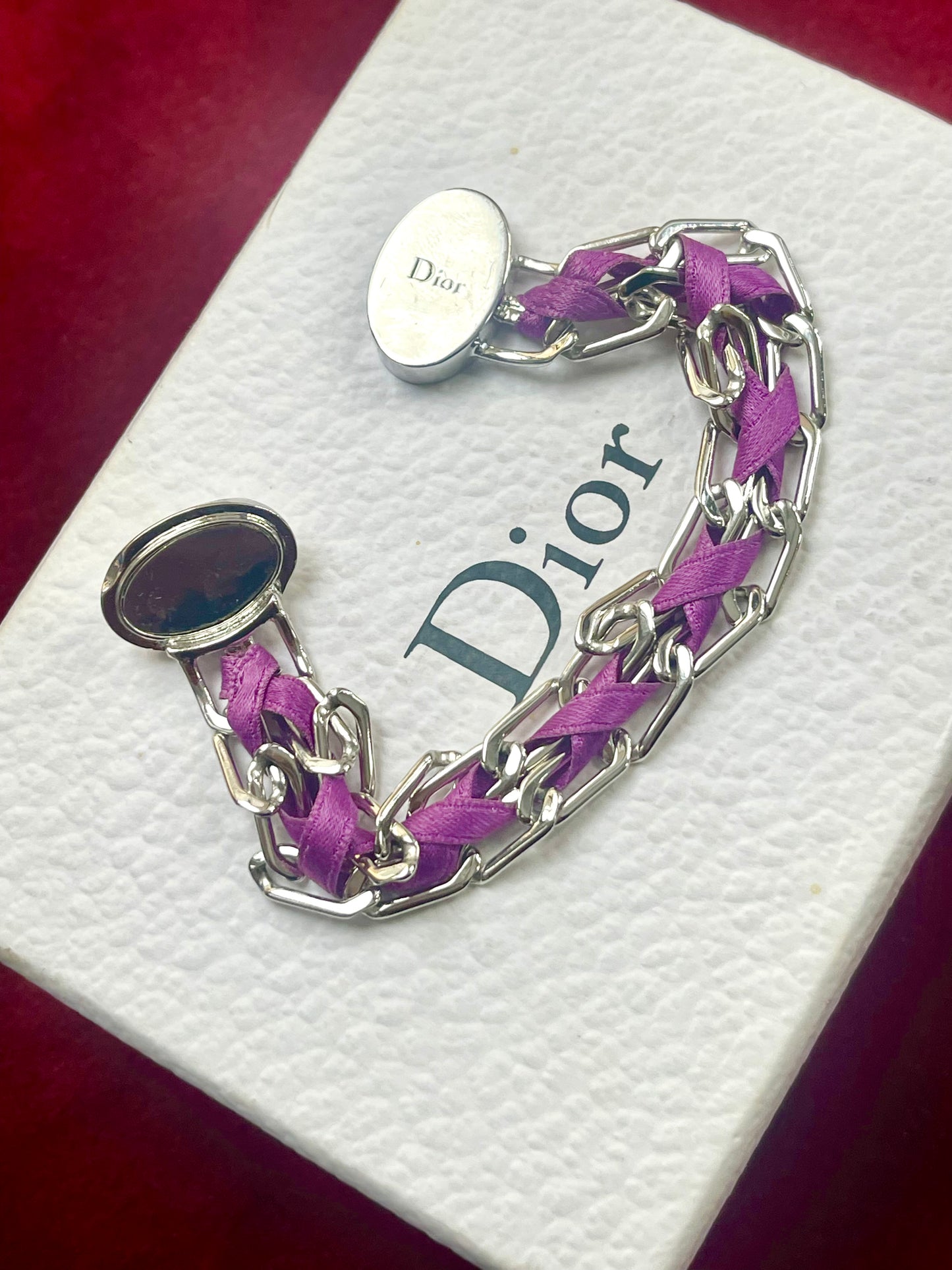 Purple braided Gourmet Dior bracelet with silver chain on a Dior branded box backside view