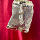 Side view of Paco Rabanne silver shoulder/wrist bag with both straps shown, on red velvet fabric background.