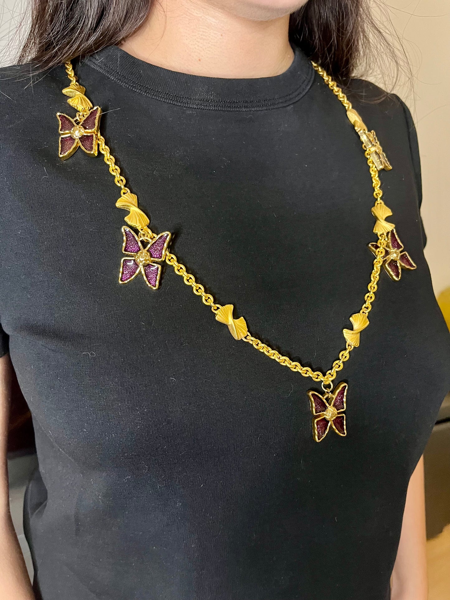 Vintage 80s five Yves Saint Laurent Butterfly Enameled pendants mounted on a Nina Ricci gold necklace, displayed on a black background worn by model