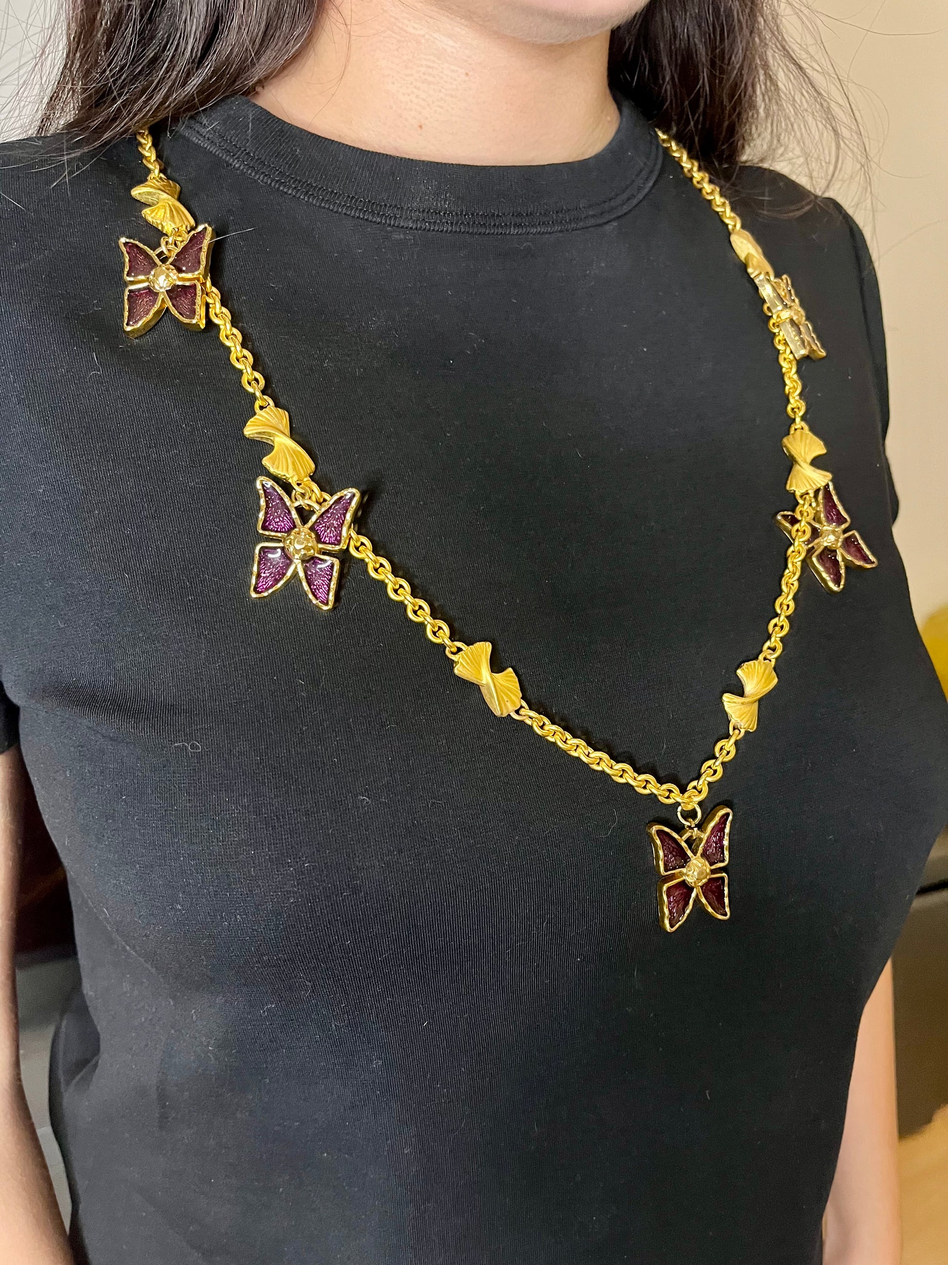 Vintage 80s five Yves Saint Laurent Butterfly Enameled pendants mounted on a Nina Ricci gold necklace, displayed on a black background worn by model