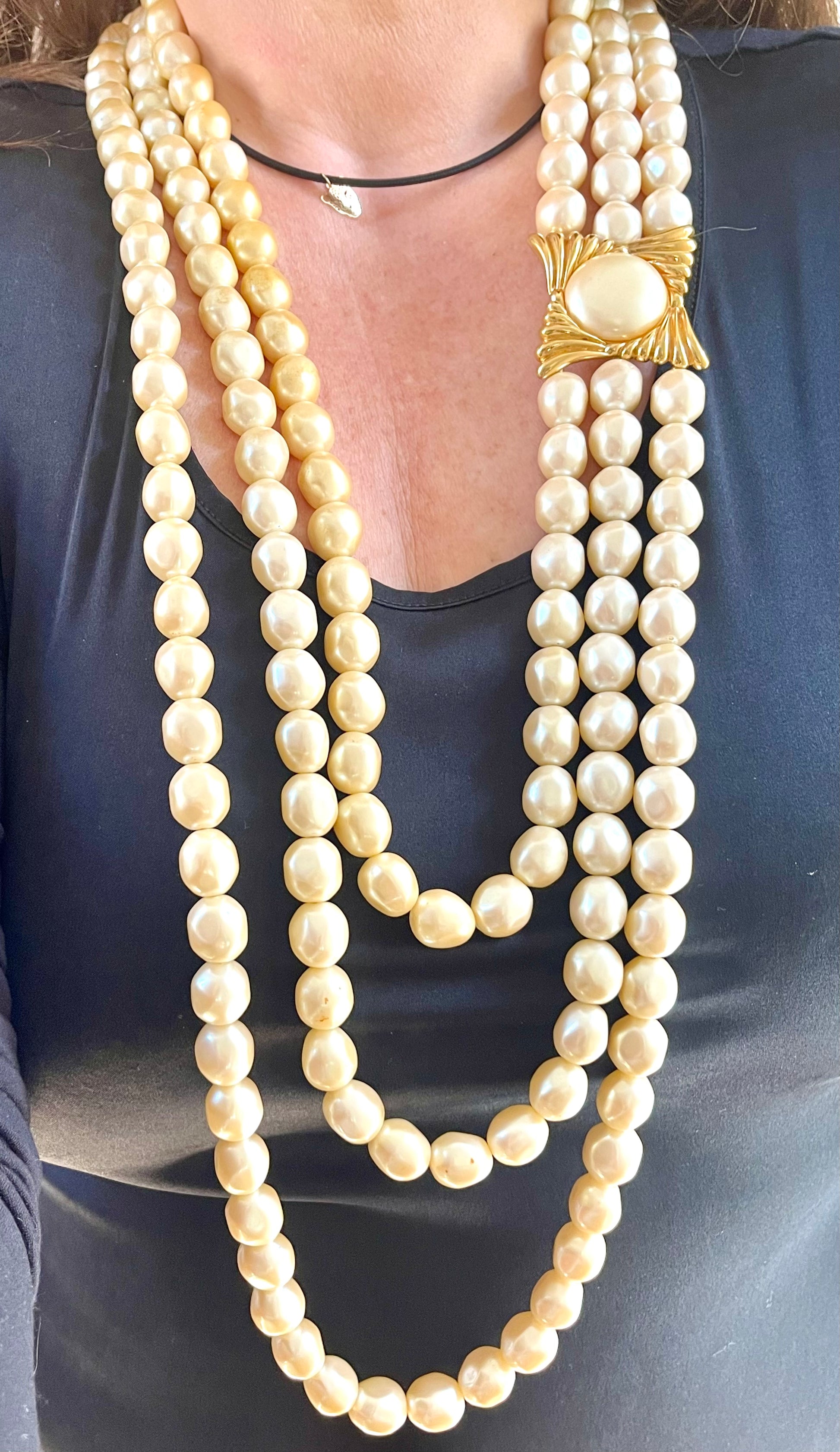 Vintage Yves Saint Laurent multi-strand pearl necklace layered with shorter leather necklace for a sophisticated, fashion-forward look.