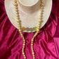 Gold beaded vintage Yves Saint Laurent necklace refurbished 18KG on a mannequin bust against a red fabric background