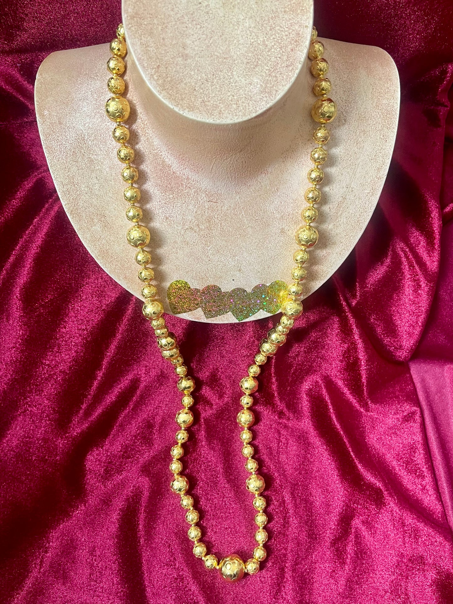 Gold beaded vintage Yves Saint Laurent necklace refurbished 18KG on a mannequin bust against a red fabric background