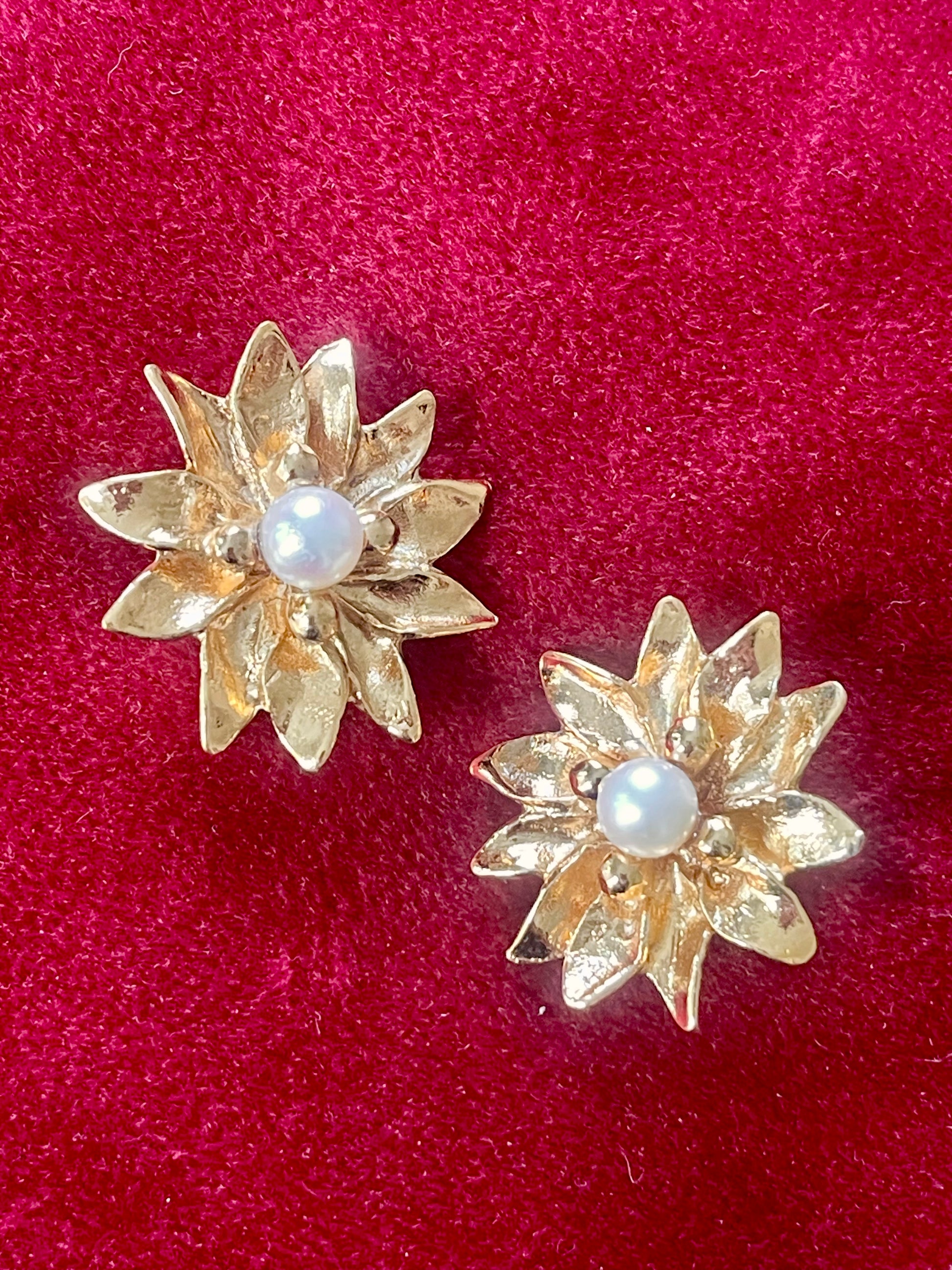 Vintage Yves Saint Laurent gold-tone floral earrings with pearl center, signed YSL Made in France, 1980s designer jewelry on a red background 