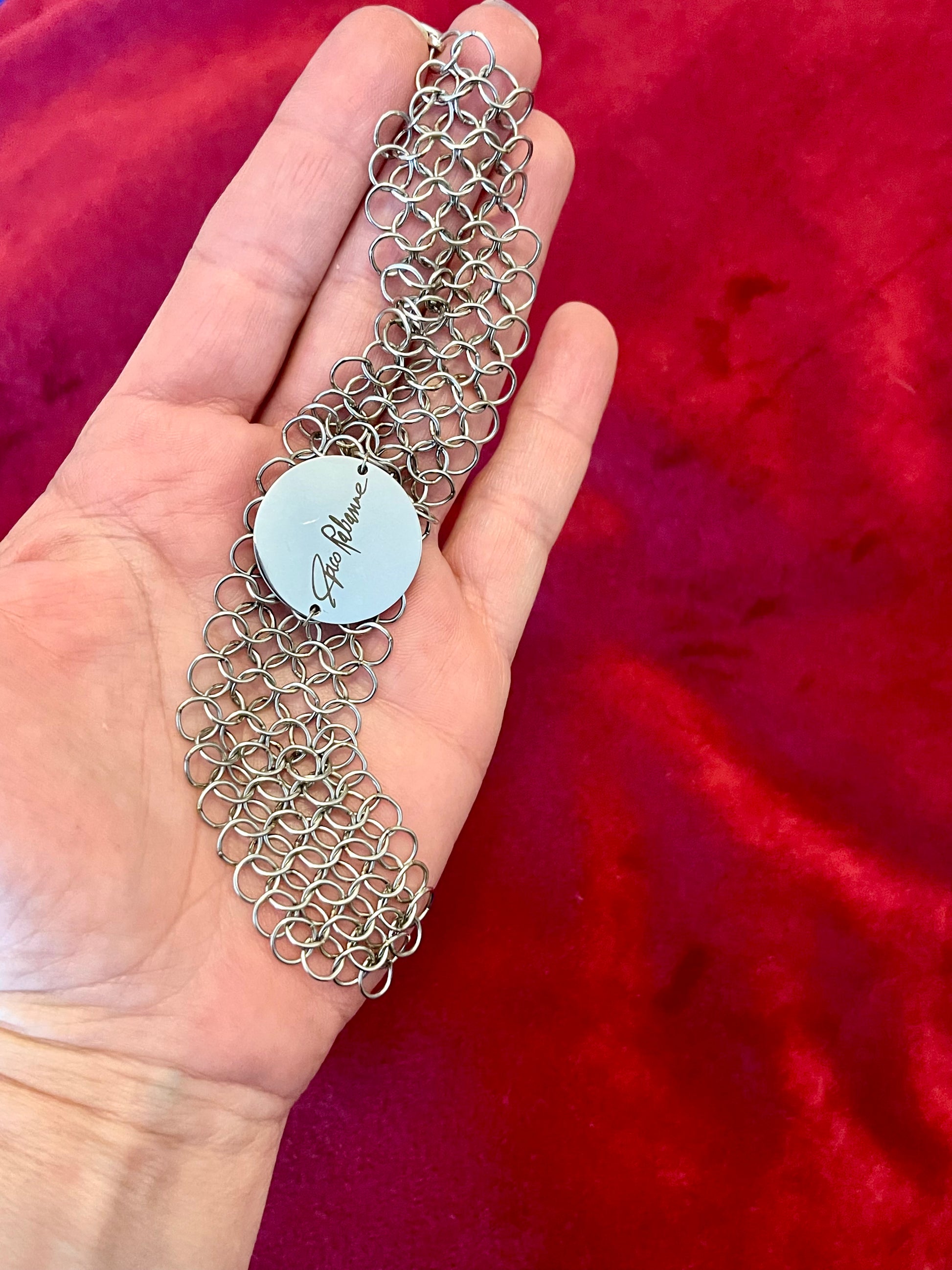 Paco Rabanne silver-tone chainmail bracelet full front view Held on hand with a red background 