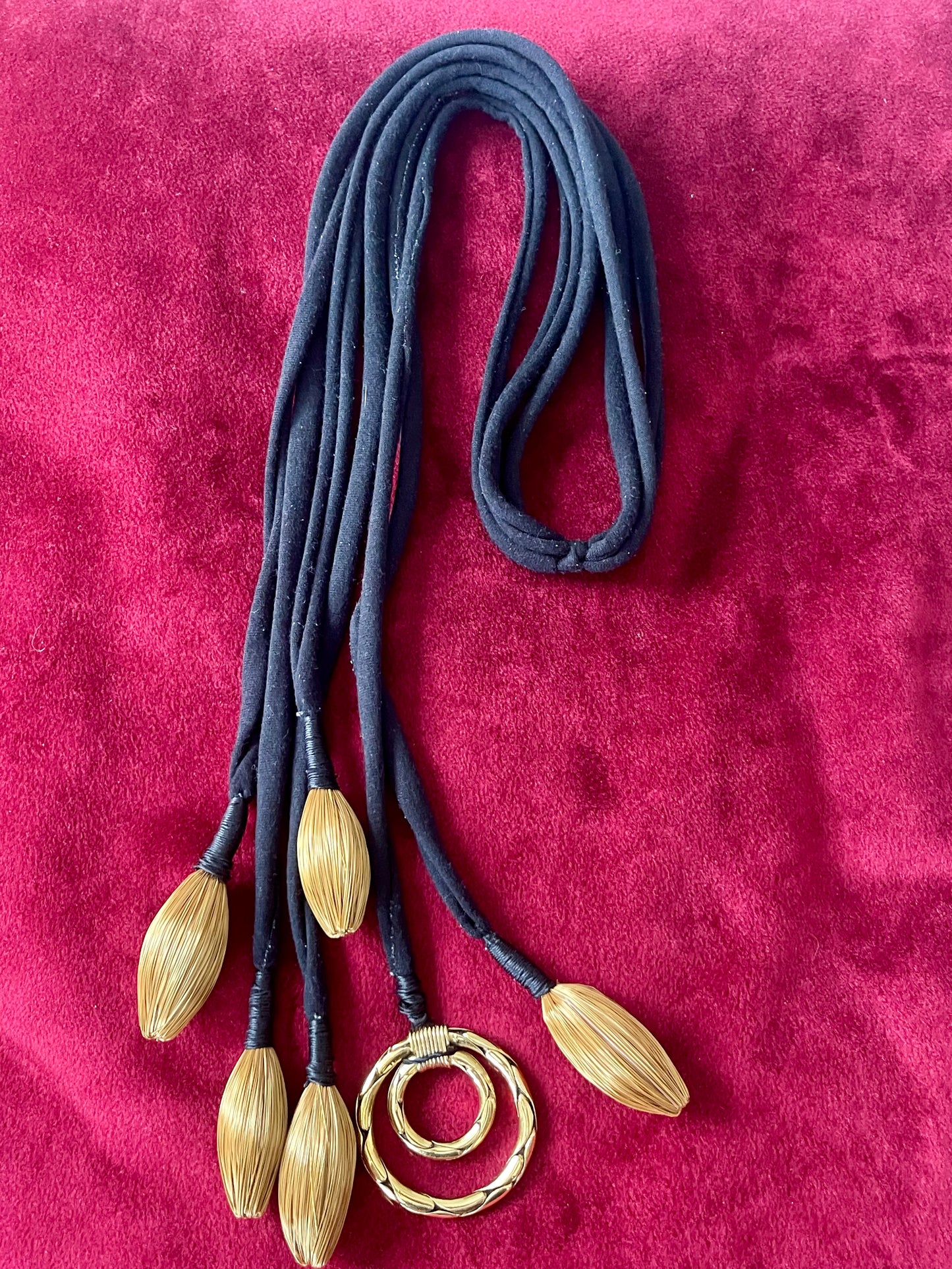 Art textile necklace with black fabric cords and gold tone pompom elements