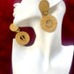 Gold earrings vintage Yves Saint Laurent with circular anchor designs on a white mannequin face 