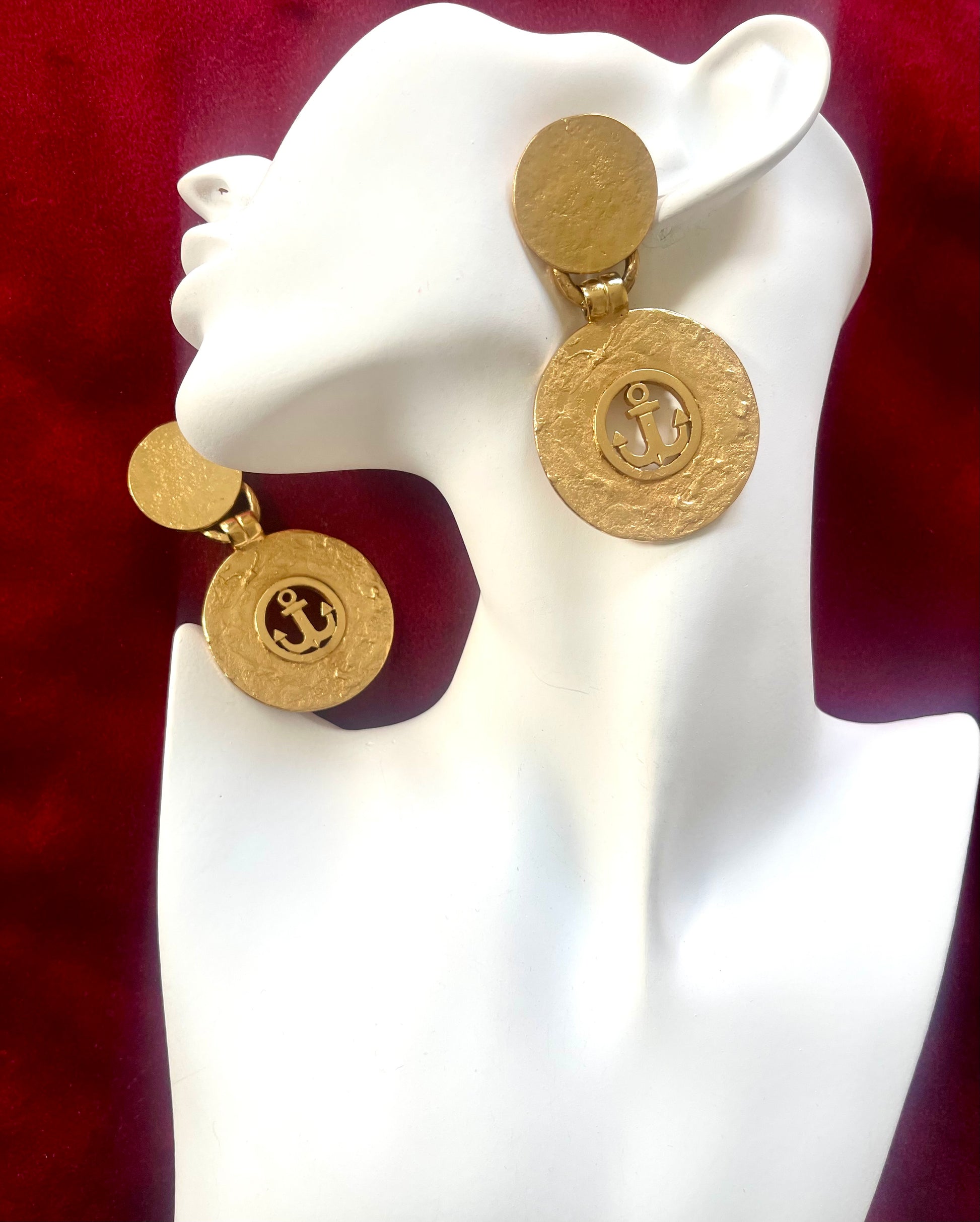 Gold earrings vintage Yves Saint Laurent with circular anchor designs on a white mannequin face 