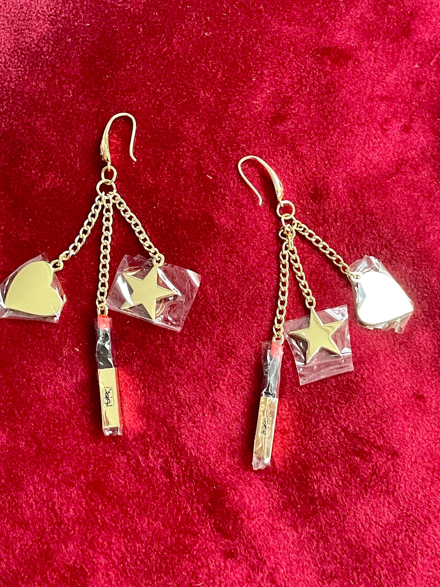 YSL Earrings displayed together showing asymmetrical design and charm arrangement on red background 