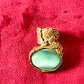 Vintage Yves Saint Laurent ring featuring a large turquoise nacre stone set in sculpted gold metal, displayed on a red velvet surface.