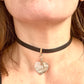 Close-up of a person wearing a black choker with a heart-shaped pendant Saint Laurent YSL
