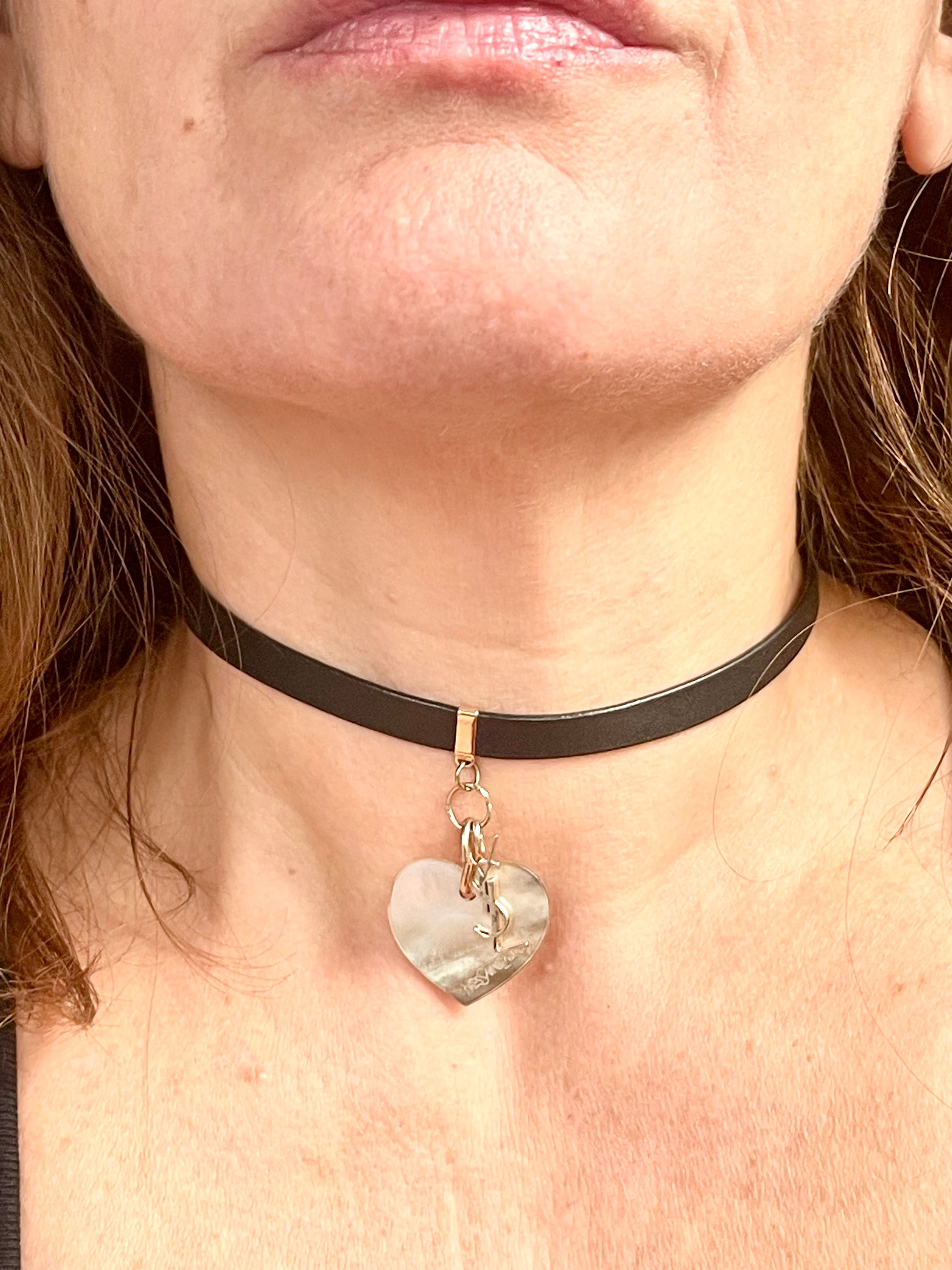 Close-up of a person wearing a black choker with a heart-shaped pendant Saint Laurent YSL