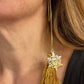 Gold earring with YSL snowflake design and tassel on a person's ear