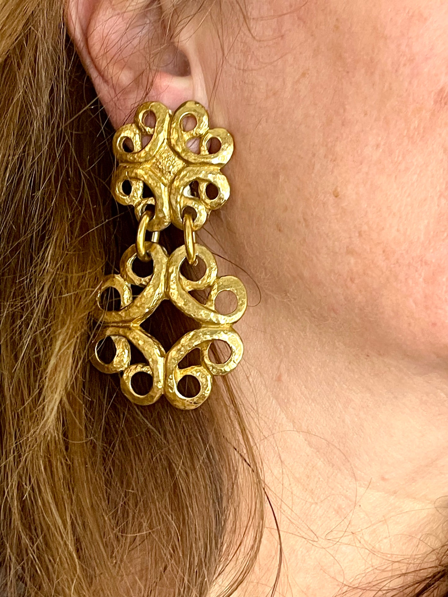 Worn by model vintage gold-tone Yves Saint Laurent statement drop earrings displayed on a red background, with a measuring tape showing approximately 8 cm length