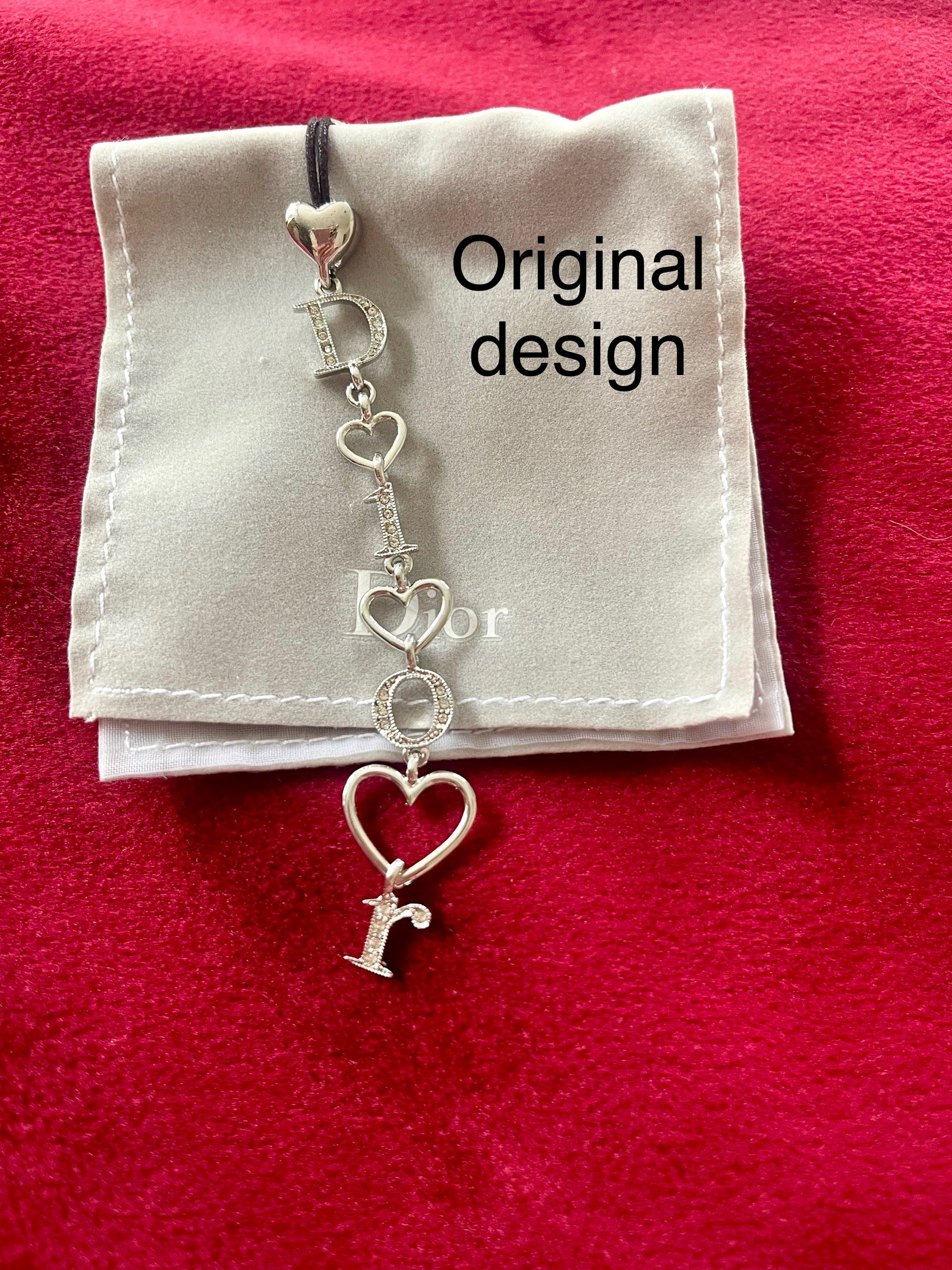 Dior phone charm original design, showing details close up with original pouch on red background 