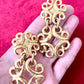 Close up view of vintage gold-tone Yves Saint Laurent statement drop earrings displayed on hand with a  red background,