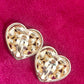 Back view of Pair of 3 cm gold-tone vintage Yves Saint Laurent heart-shaped clip-on earrings decorated with multi-colored crystals, displayed on a red background showing signature 