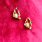 Vintage Yves Saint Laurent gold-tone calla lily earrings with pearl centers, sculptural floral design on a red background 