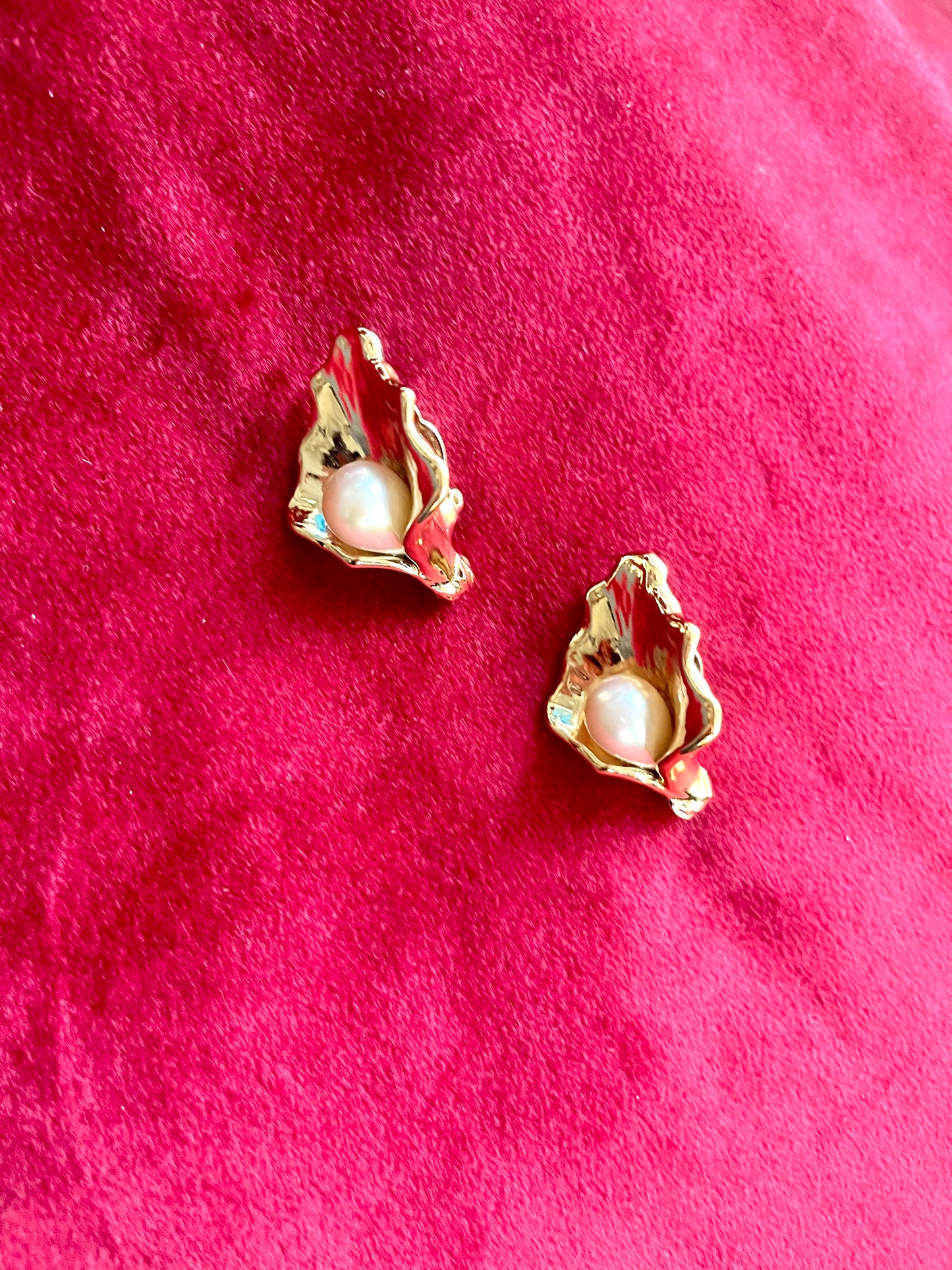 Vintage Yves Saint Laurent gold-tone calla lily earrings with pearl centers, sculptural floral design on a red background 