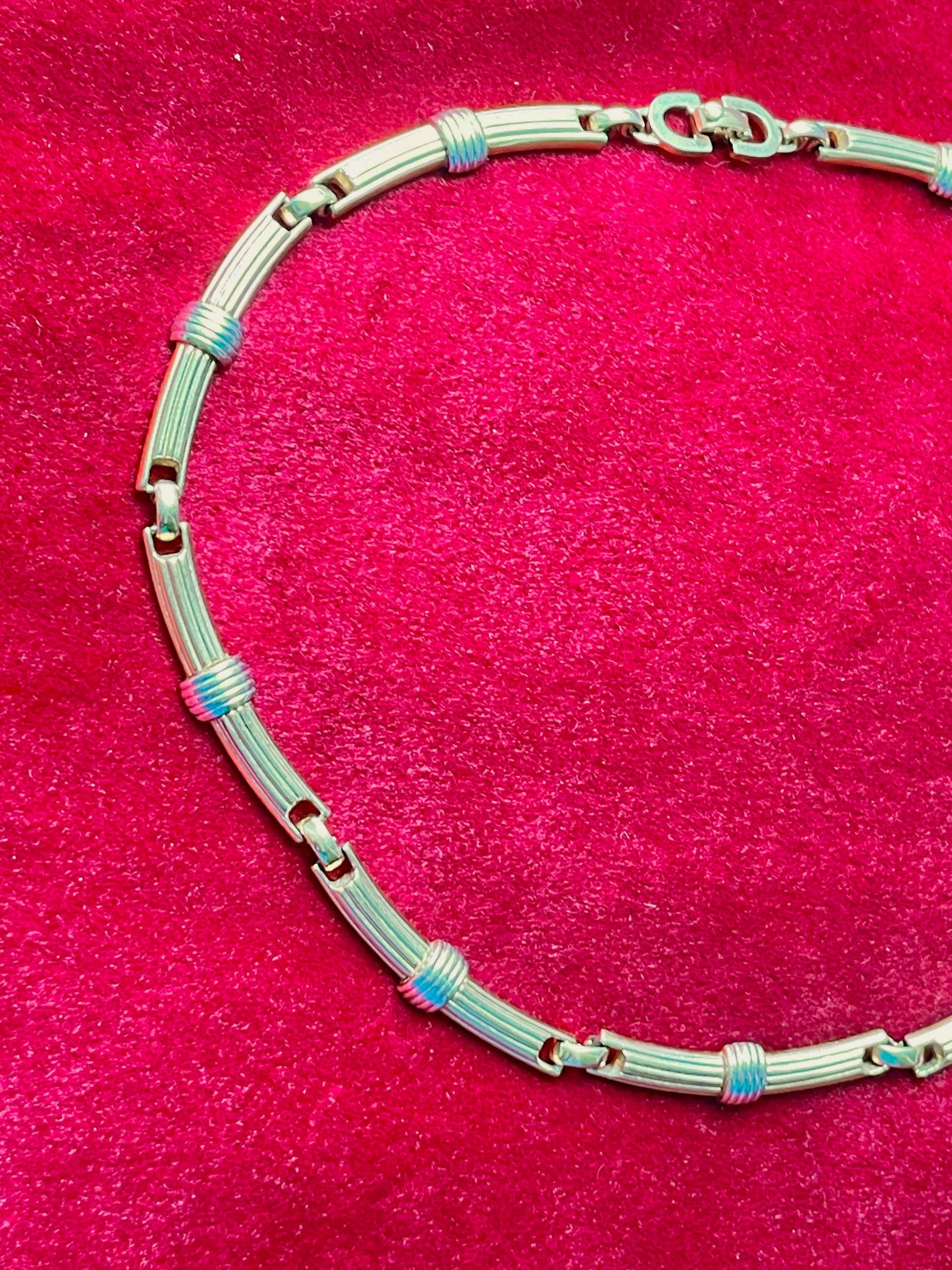 Vintage Christian Dior two-tone necklace with ribbed accents displayed on a red velvet background
