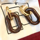 Paco Rabanne XL Link earrings in brown resin and gold metal, front view,Included pouch on red background 