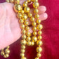 Held by hand Close-up of YSL vintage gold bead necklace showing 18K refurbished shine and textured detailing vintage Yves Saint Laurent 