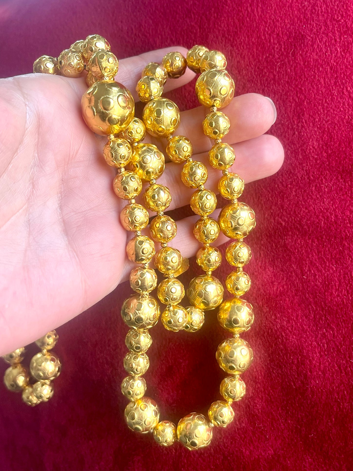 Held by hand Close-up of YSL vintage gold bead necklace showing 18K refurbished shine and textured detailing vintage Yves Saint Laurent 
