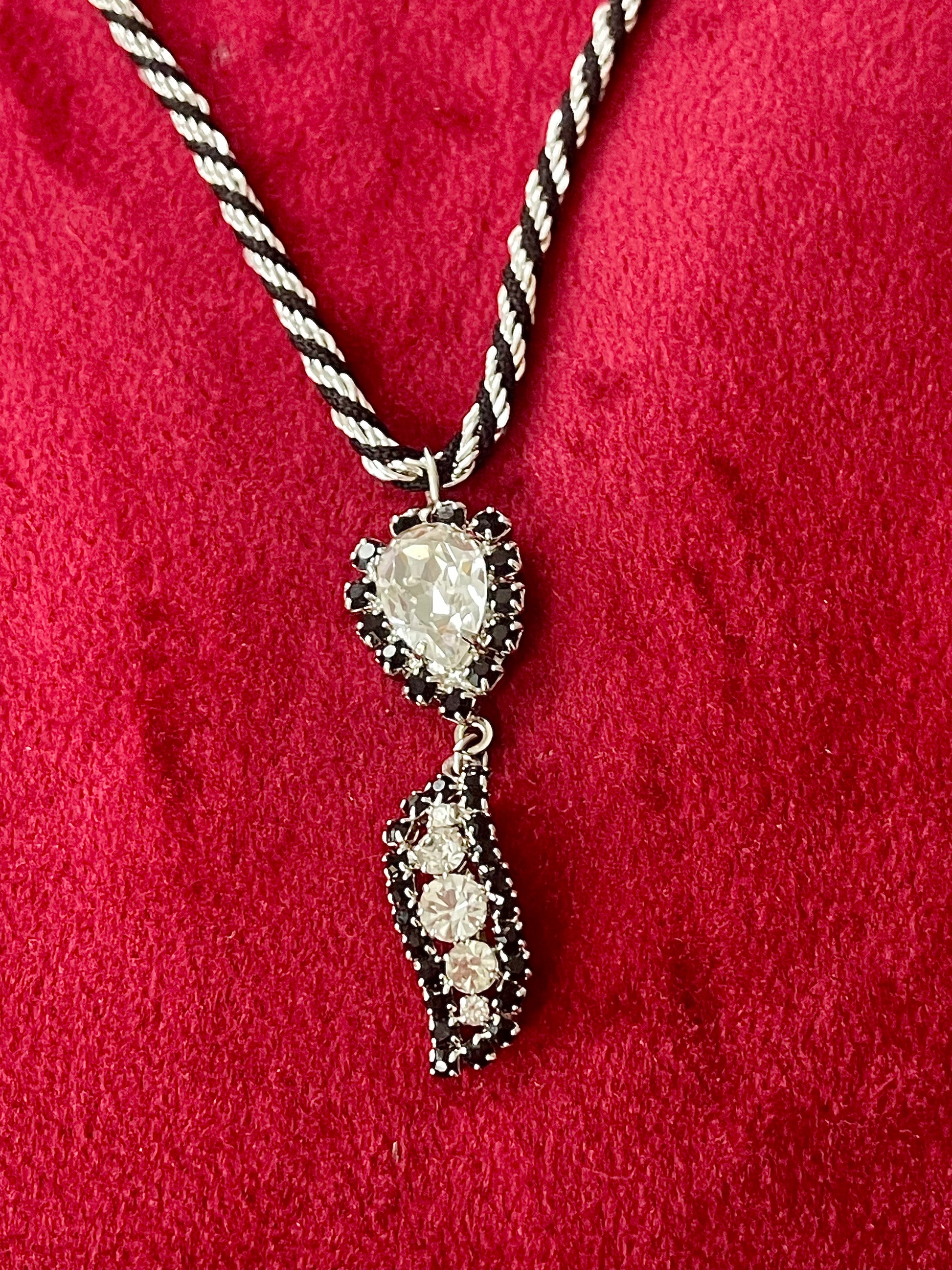 Close up on vintage Christian Dior rhinestone pendant with Trifari necklace against a red background 