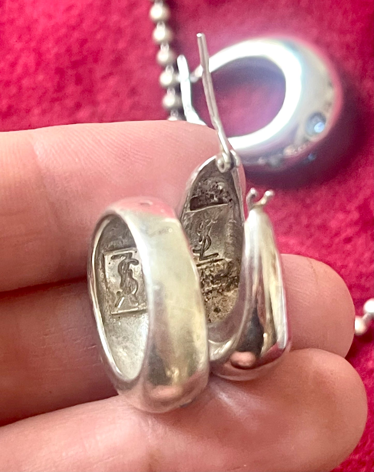 Close-up of back side vintage YSL jewelry set: silver earrings with blue stones, cross pendant necklace, and matching ring Showing the hallmarks 