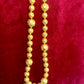 Close-up of YSL vintage gold bead necklace showing 18K refurbished shine and textured detailing with tag shown vintage Yves Saint Laurent 