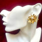 Yves Saint Laurent vintage 80s Gold flower-shaped earring with pearl center on a white mannequin ear against a red background