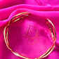 Gold bracelet on a pink fabric background with Christian Dior logo